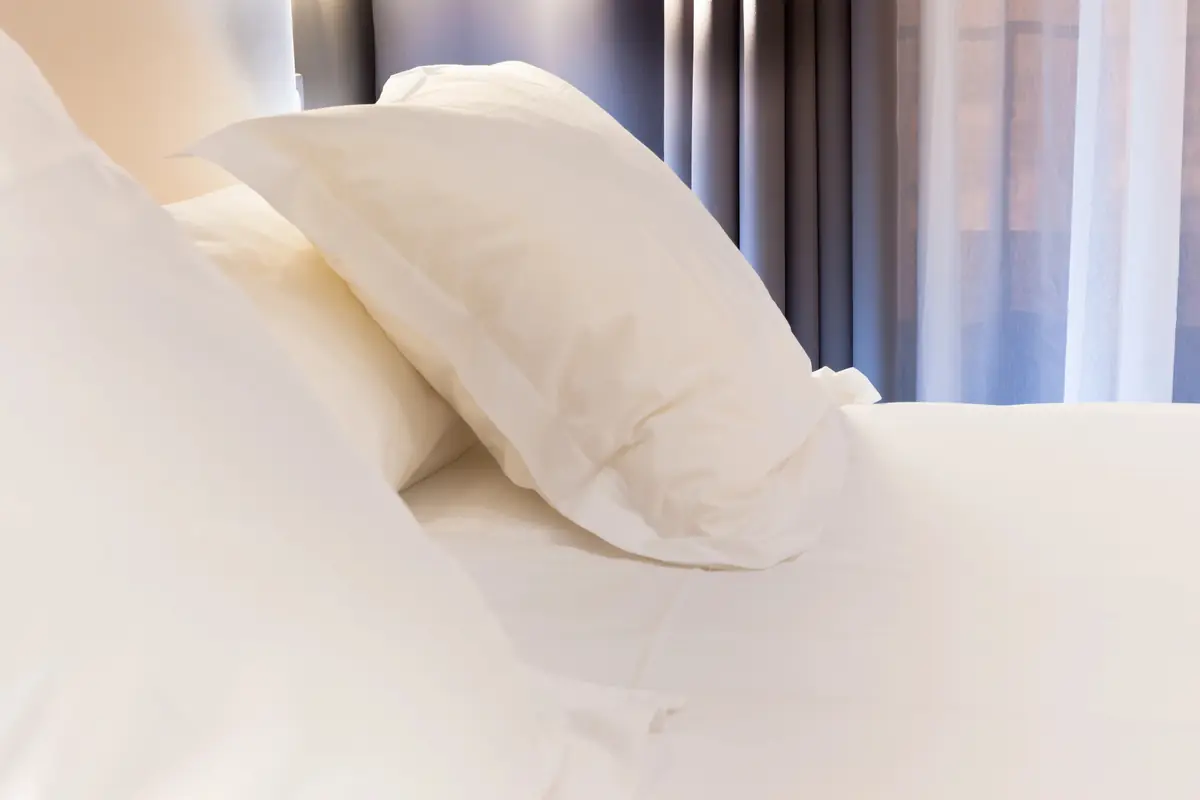 Lit d’hôtel aux draps et oreillers blancs